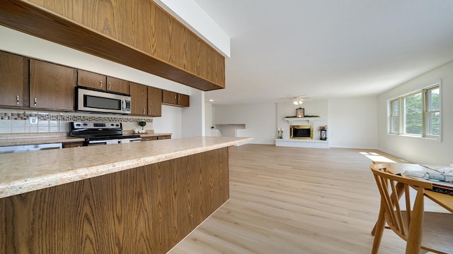 1320 Lake Summerset Rd, Davis, IL 61019 - kitchen featuring appliances with stainless steel finishes, light countertops, tasteful backsplash, light wood-style flooring, and a brick fireplace