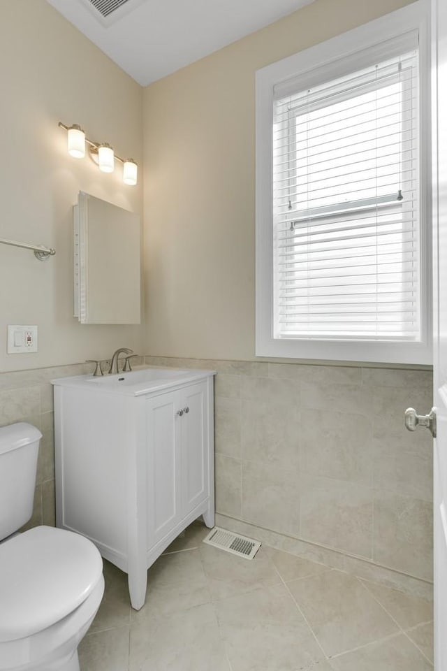 2732 W Belmont Ave, Chicago, IL 60618 - bathroom featuring tile walls, tile patterned flooring, vanity, and a wainscoted wall
