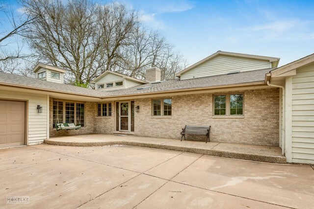 7S745 State Route 53rd Hwy, Naperville, IL 60540 - rear view of house featuring brick siding, an attached garage, roof with shingles, a chimney, and a patio