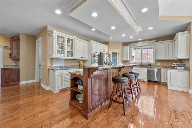 675 Oak Ln, South Elgin, IL 60177 - kitchen with appliances with stainless steel finishes, a kitchen breakfast bar, light wood-style flooring, white cabinetry, and glass insert cabinets