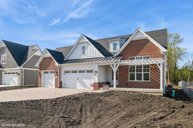 view of front of property with a garage, board and batten siding, a standing seam roof, driveway, and brick siding