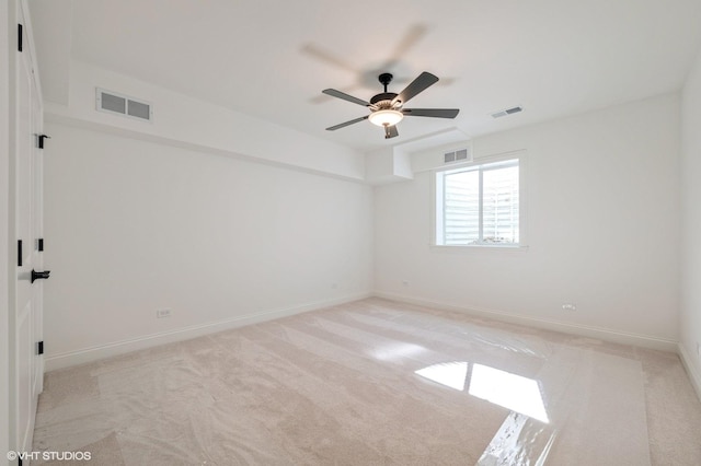 spare room featuring light colored carpet and a ceiling fan