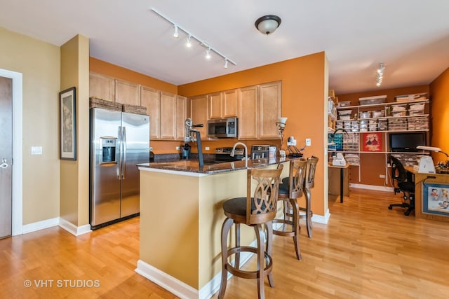 1841 S Calumet Ave Unit 1304, Chicago, IL 60616 - kitchen featuring appliances with stainless steel finishes, light wood-style flooring, a breakfast bar area, light brown cabinetry, and a peninsula