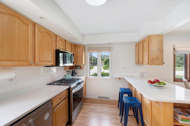 602 E Park Ave, Elmhurst, IL 60126 - kitchen with appliances with stainless steel finishes, a peninsula, a breakfast bar area, and plenty of natural light