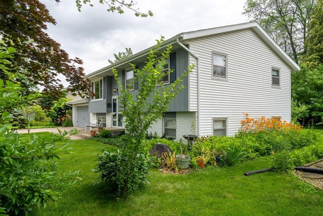 212 Rebecca Ln, Normal, IL 61761 - view of side of home featuring an attached garage, a yard, brick siding, and driveway