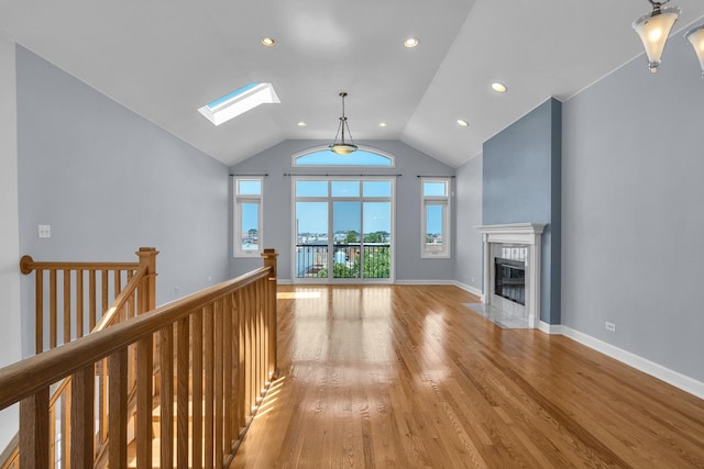 7153 W Irving Park Rd Unit 3, Chicago, IL 60634 - unfurnished living room featuring a skylight, light wood-type flooring, a fireplace with flush hearth, recessed lighting, and high vaulted ceiling