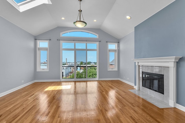 7153 W Irving Park Rd Unit 3, Chicago, IL 60634 - unfurnished living room featuring a tile fireplace, vaulted ceiling, light wood-style flooring, and a skylight