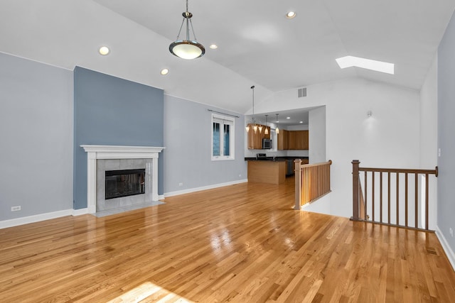 7153 W Irving Park Rd Unit 3, Chicago, IL 60634 - unfurnished living room with vaulted ceiling, light wood finished floors, recessed lighting, a skylight, and a tile fireplace