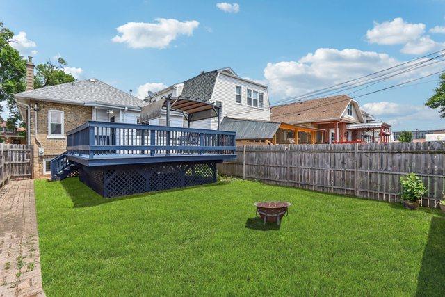 5639 W Cornelia Ave, Chicago, IL 60634 - fenced backyard featuring a wooden deck and a fire pit
