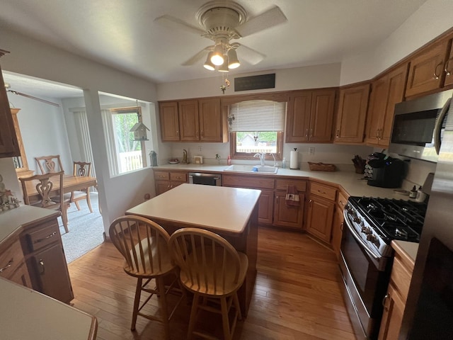 24005 S Green Heron Dr, Channahon, IL 60410 - kitchen with appliances with stainless steel finishes, light countertops, a ceiling fan, light wood-style flooring, and a center island