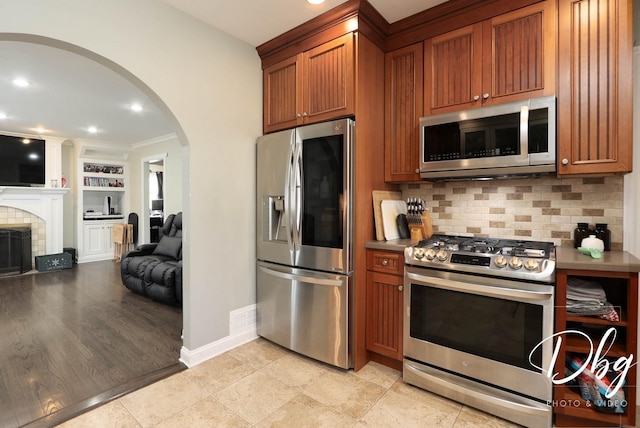 34119 N Hainesville Rd, Round Lake, IL 60073 - kitchen featuring stainless steel appliances, arched walkways, open floor plan, brown cabinetry, and tasteful backsplash