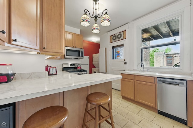 1235 E 53rd St Unit 3, Chicago, IL 60615 - kitchen featuring appliances with stainless steel finishes, light tile patterned floors, a breakfast bar, a peninsula, and hanging light fixtures