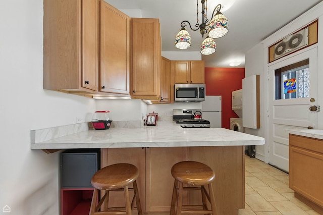 1235 E 53rd St Unit 3, Chicago, IL 60615 - kitchen featuring stainless steel appliances, estacked washer and dryer, light countertops, a breakfast bar area, and a peninsula