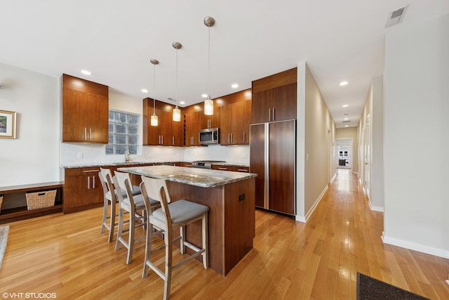 2033 N Damen Ave Unit 2N, Chicago, IL 60647 - kitchen with stainless steel appliances, a breakfast bar, a kitchen island, light wood-type flooring, and pendant lighting