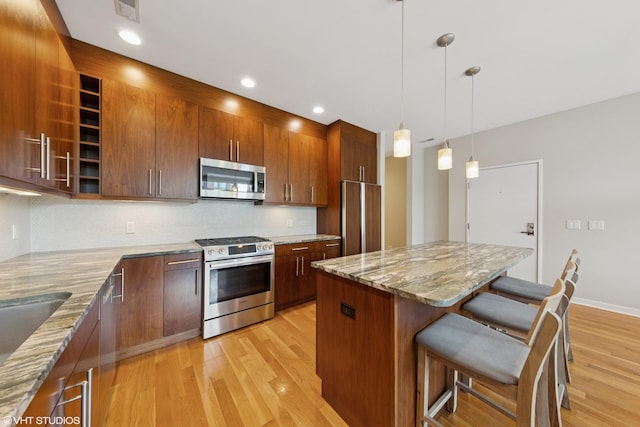 2033 N Damen Ave Unit 2N, Chicago, IL 60647 - kitchen with stainless steel appliances, a breakfast bar area, light wood-style flooring, decorative backsplash, and light stone counters