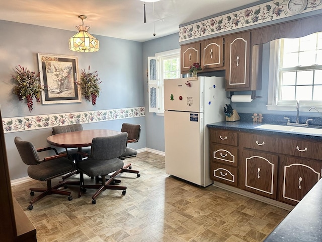 411 1st Ave, Ottawa, IL 61350 - kitchen with freestanding refrigerator, dark brown cabinetry, hanging light fixtures, and dark countertops