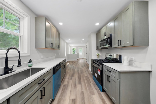 114 Maple St, Mchenry, IL 60051 - kitchen featuring stainless steel microwave, gas range, dishwasher, light wood-style floors, and gray cabinetry