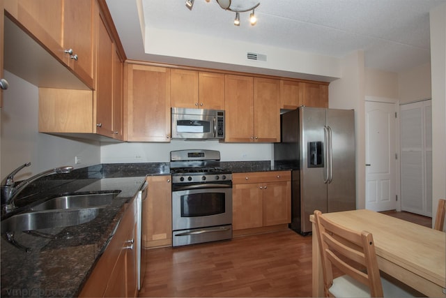 8440 Callie Ave Unit 410, Morton Grove, IL 60053 - kitchen featuring appliances with stainless steel finishes, brown cabinets, dark wood-style flooring, and dark stone counters