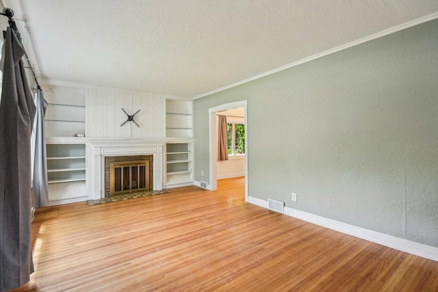 237 Le Grande Blvd, Aurora, IL 60506 - unfurnished living room featuring built in features, light wood-type flooring, crown molding, a textured ceiling, and a glass covered fireplace