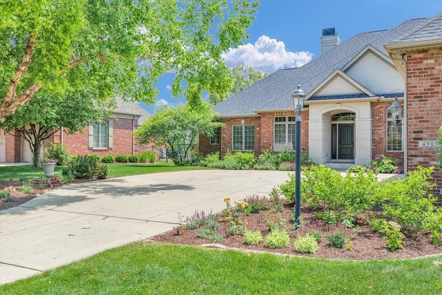 4905 Peifer Ln, Champaign, IL 61822 - view of front of property featuring roof with shingles, a front yard, a chimney, and brick siding