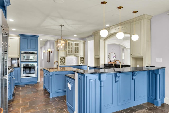 4905 Peifer Ln, Champaign, IL 61822 - kitchen with blue cabinetry, a kitchen island with sink, a breakfast bar area, dark stone countertops, and recessed lighting