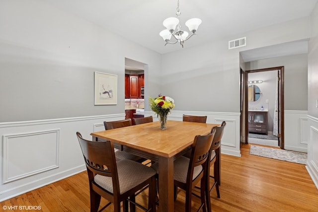 4503 N Ashland Ave Unit 2N, Chicago, IL 60640 - dining room with a wainscoted wall, a chandelier, light wood finished floors, and a decorative wall