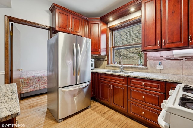 4503 N Ashland Ave Unit 2N, Chicago, IL 60640 - kitchen featuring freestanding refrigerator, white gas stove, light wood-type flooring, backsplash, and light stone counters
