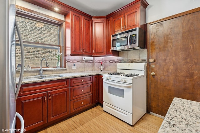 4503 N Ashland Ave Unit 2N, Chicago, IL 60640 - kitchen featuring appliances with stainless steel finishes, reddish brown cabinets, light wood finished floors, and decorative backsplash