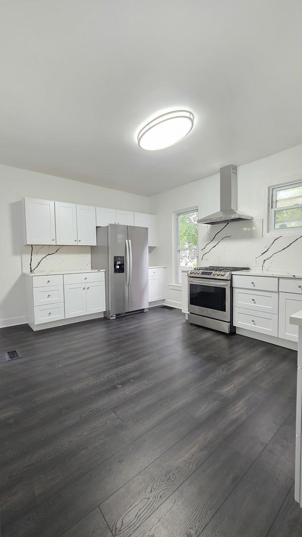 208 N Chestnut St, Aurora, IL 60506 - kitchen featuring stainless steel appliances, wall chimney range hood, dark wood-style flooring, and white cabinets