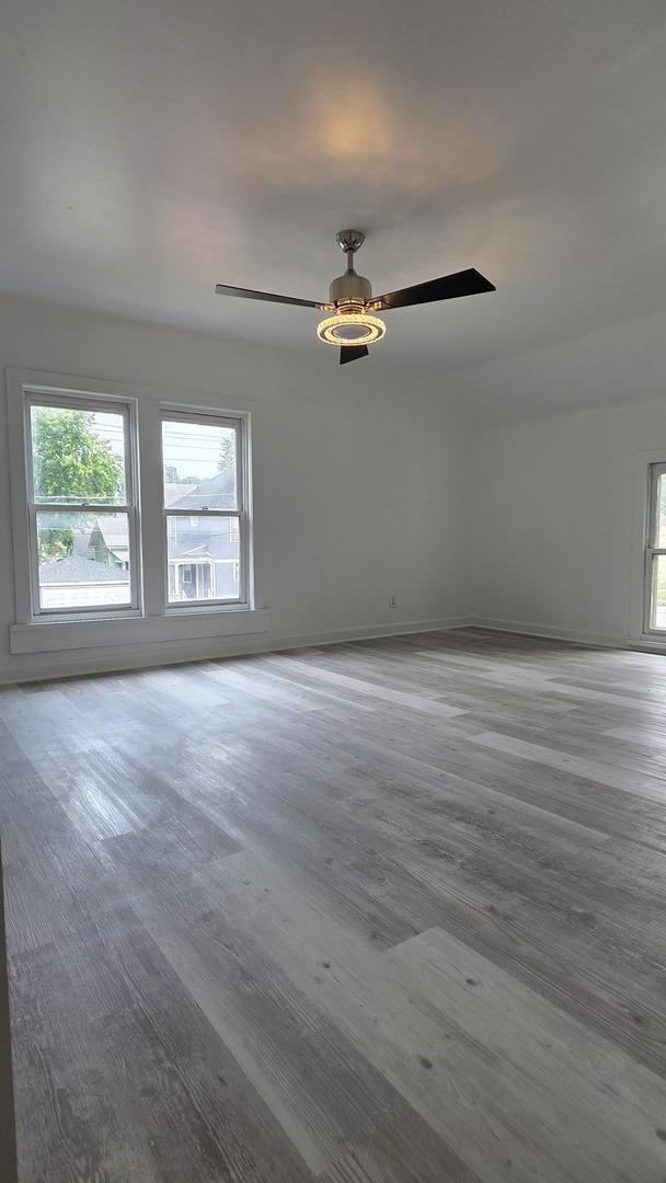 208 N Chestnut St, Aurora, IL 60506 - empty room featuring healthy amount of natural light, a ceiling fan, and wood finished floors