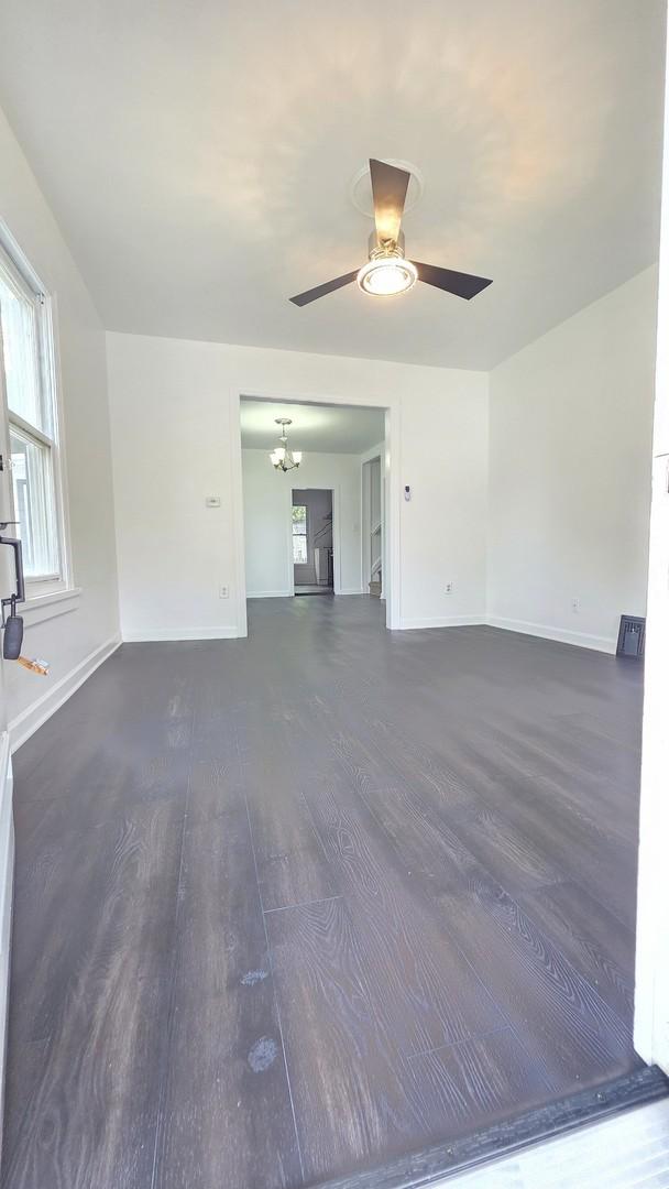 208 N Chestnut St, Aurora, IL 60506 - unfurnished living room featuring dark wood-style floors, a ceiling fan, and a chandelier