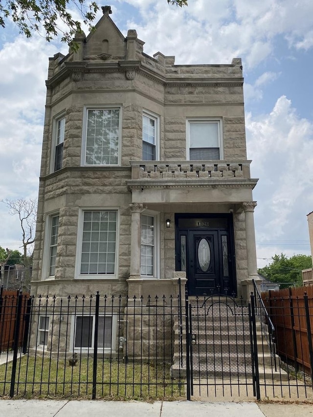 1826 S Drake Ave, Chicago, IL 60623 - view of front facade featuring stone siding, a fenced front yard, and a gate