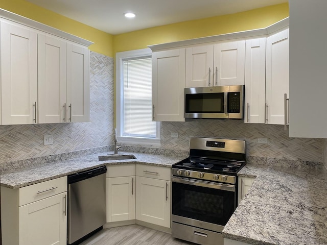 1826 S Drake Ave, Chicago, IL 60623 - kitchen with appliances with stainless steel finishes, white cabinets, backsplash, light stone counters, and light wood-style floors