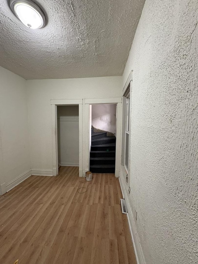 5604 S Morgan St, Chicago, IL 60621 - unfurnished bedroom with wood finished floors, a textured wall, multiple closets, and a textured ceiling