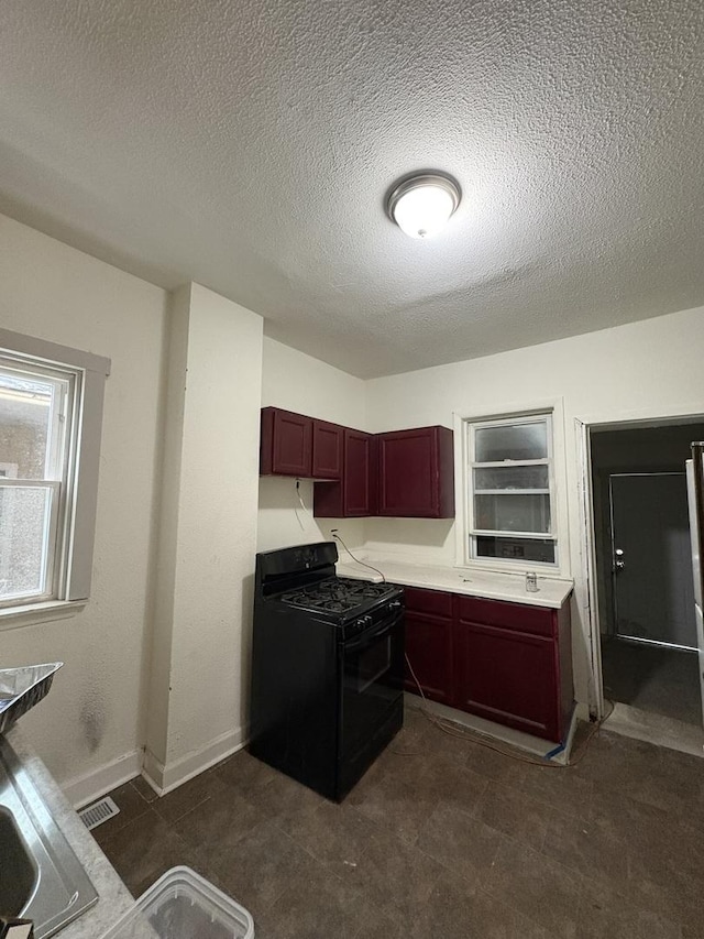 5604 S Morgan St, Chicago, IL 60621 - kitchen featuring black gas stove, reddish brown cabinets, a textured ceiling, and light countertops
