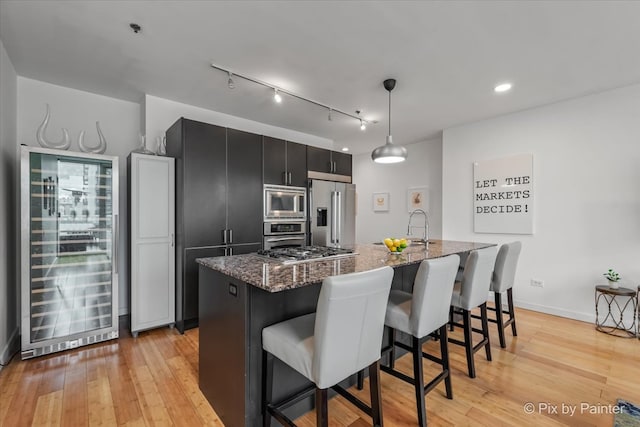 653 N Kingsbury St Unit 706, Chicago, IL 60654 - kitchen with appliances with stainless steel finishes, beverage cooler, dark cabinetry, a kitchen breakfast bar, and an island with sink