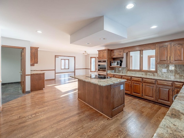 501 Bryan Trl, New Lenox, IL 60451 - kitchen with stainless steel appliances, a center island, light stone counters, decorative backsplash, and plenty of natural light