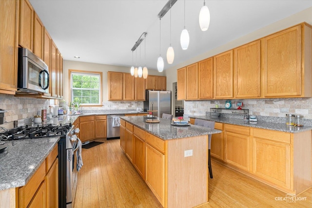 16260 W Mohawk Ct, Lockport, IL 60441 - kitchen with appliances with stainless steel finishes, a kitchen island, light wood-type flooring, and tasteful backsplash