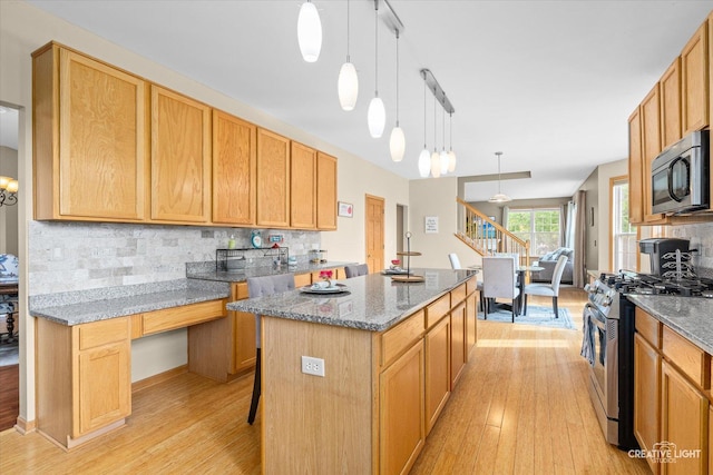 16260 W Mohawk Ct, Lockport, IL 60441 - kitchen featuring appliances with stainless steel finishes, a kitchen island, light wood-style floors, tasteful backsplash, and stone counters