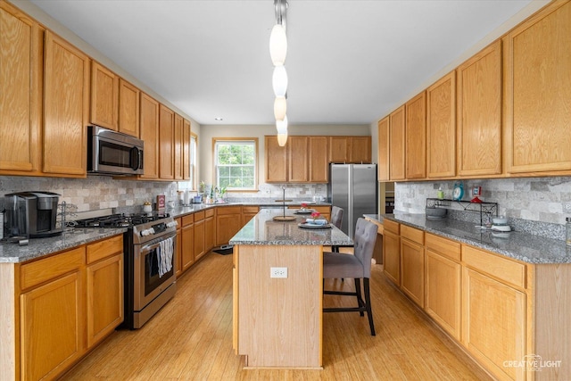 16260 W Mohawk Ct, Lockport, IL 60441 - kitchen with appliances with stainless steel finishes, light wood-style flooring, a kitchen bar, and backsplash