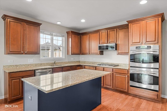 13311 Morning Mist Pl, Plainfield, IL 60585 - kitchen with appliances with stainless steel finishes, light wood finished floors, a kitchen island, recessed lighting, and light stone countertops