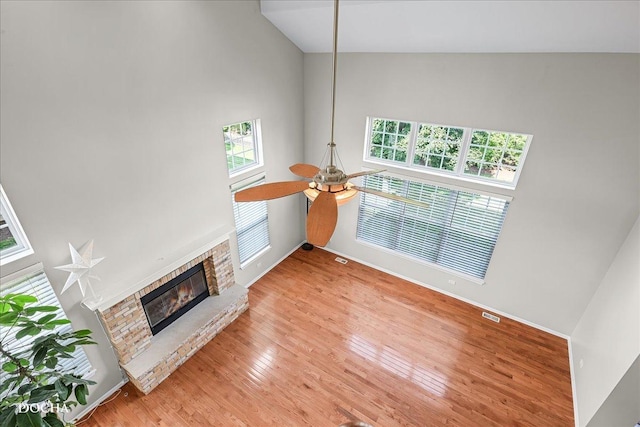 13311 Morning Mist Pl, Plainfield, IL 60585 - unfurnished living room with ceiling fan, plenty of natural light, a stone fireplace, light wood-style flooring, and a towering ceiling