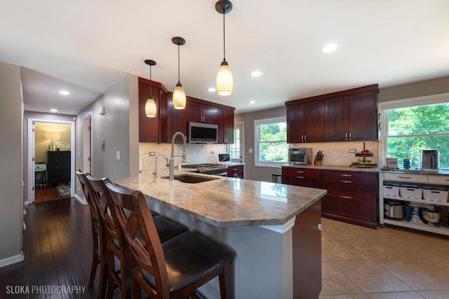 106 Grand Central Ln, Schaumburg, IL 60193 - kitchen with stainless steel microwave, backsplash, light stone countertops, recessed lighting, and a peninsula