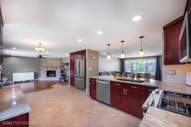 106 Grand Central Ln, Schaumburg, IL 60193 - kitchen with appliances with stainless steel finishes, open floor plan, reddish brown cabinets, a brick fireplace, and recessed lighting