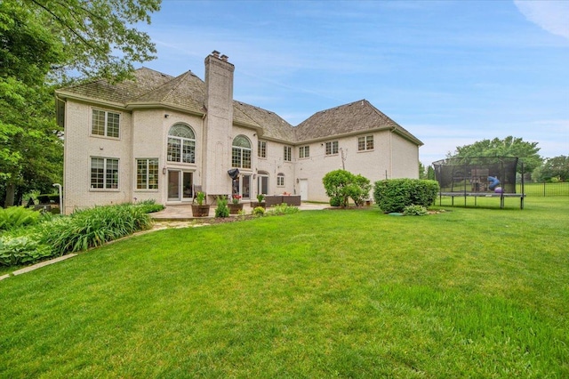 14695 Fox Hollow Ln, Lemont, IL 60439 - rear view of house with a trampoline, a chimney, a lawn, and a patio