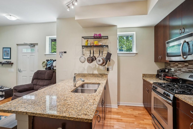 1159 N Hudson St Unit 1-101, Chicago, IL 60610 - kitchen with appliances with stainless steel finishes, a peninsula, light wood-style floors, backsplash, and light stone countertops