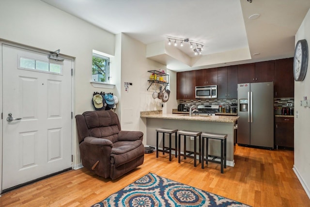 1159 N Hudson St Unit 1-101, Chicago, IL 60610 - kitchen with stainless steel appliances, a breakfast bar area, backsplash, a peninsula, and light wood-style flooring