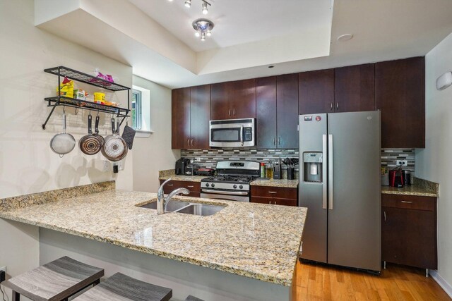 1159 N Hudson St Unit 1-101, Chicago, IL 60610 - kitchen featuring appliances with stainless steel finishes, a peninsula, a breakfast bar, light wood-style flooring, and decorative backsplash
