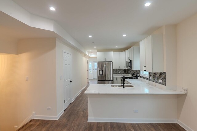 1131 S Ridgeland Ave, Oak Park, IL 60304 - kitchen featuring appliances with stainless steel finishes, a peninsula, decorative backsplash, dark wood-style flooring, and recessed lighting