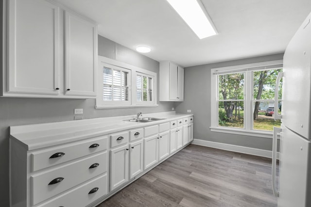 3225 Gilead Ave, Zion, IL 60099 - kitchen with freestanding refrigerator, light countertops, white cabinetry, and light wood-style flooring